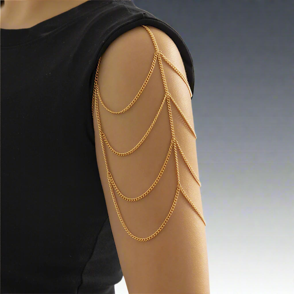 A woman wearing a multilayered gold shoulder chain bracelet draping over the arm.