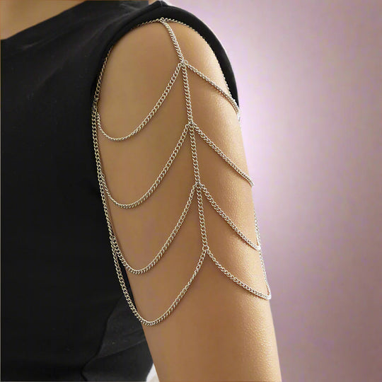 A woman wearing a multilayered silver shoulder chain bracelet draping over the arm.