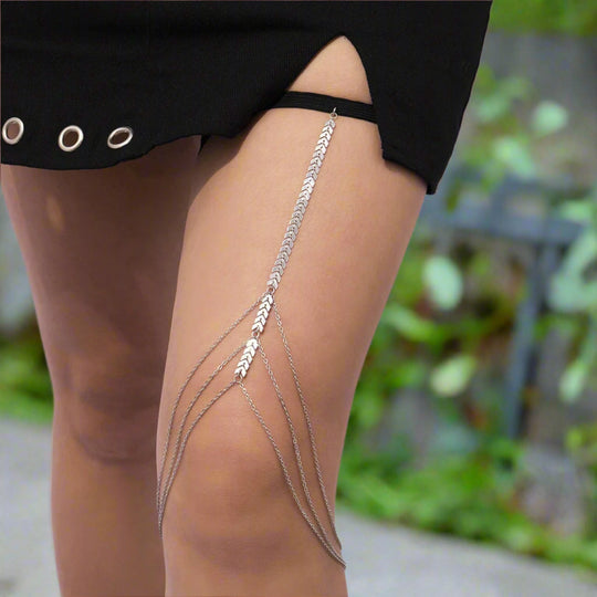 Silver leg chain worn by a person with a blurred outdoor background